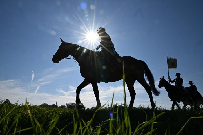 Drei Reiter erscheinen im Gegenlicht als Schatten vor blauem Himmel