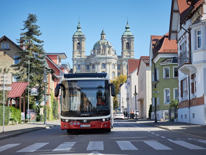 Ein Elektrobus fährt in der Abt-Hyller-Straße in Weingarten. Im Hintergrund die Basilika.