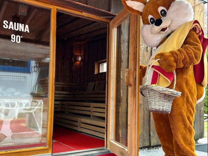 Ein lebensgroßer Plüschosterhase hält die Tür zur Sauna auf, in der Hand einen Osterkorb