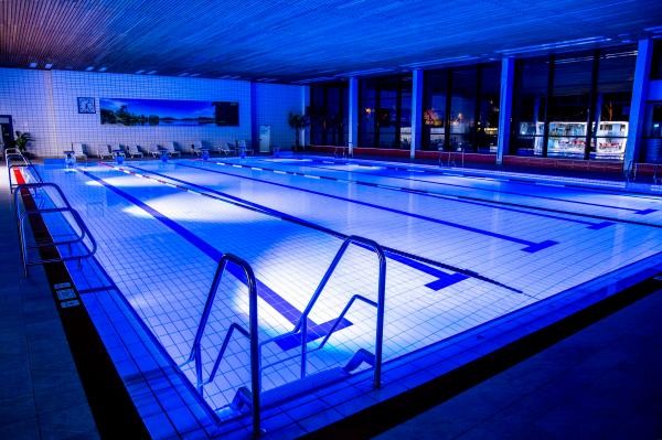 Blick auf das beleuchtete Schwimmerbecken des Hallenbades