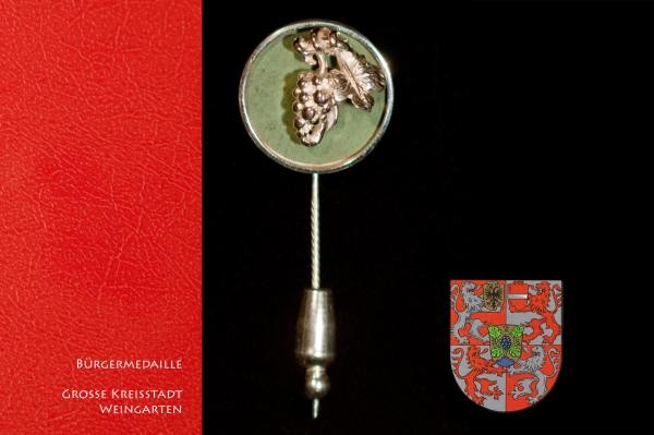 Die Bürgermedaille ist eine kleine Nadel aus Silber. Sie zeigt eine Weinrebe.