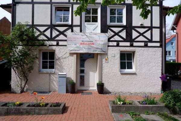 Blick auf die Fassade des Integrationszentrums. Über der Eingangstüre heißt ein Plakat die Besucher willkommen.