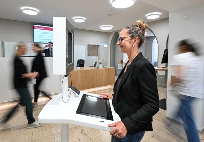 Eien Frau steht im Amtshaus an einem Terminal, um ein biometrisches Porträtfoto von sich machen zu lassen.