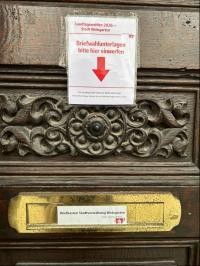 Ein Pfeil auf einem Zettel zeigt auf einen goldenen Briefkasten 