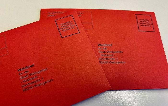 Zwei rote Briefumschläge, aufgedruckt die Adresse der Stadt