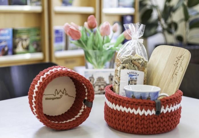 Vesperbrettchen, Häkelkörbchen in den Stadtfarben Weiß und Rot, Basilikanudeln: auf einem Tisch in der Tourist-Info stehen einige der Souvenirs, die hier verkauft werden