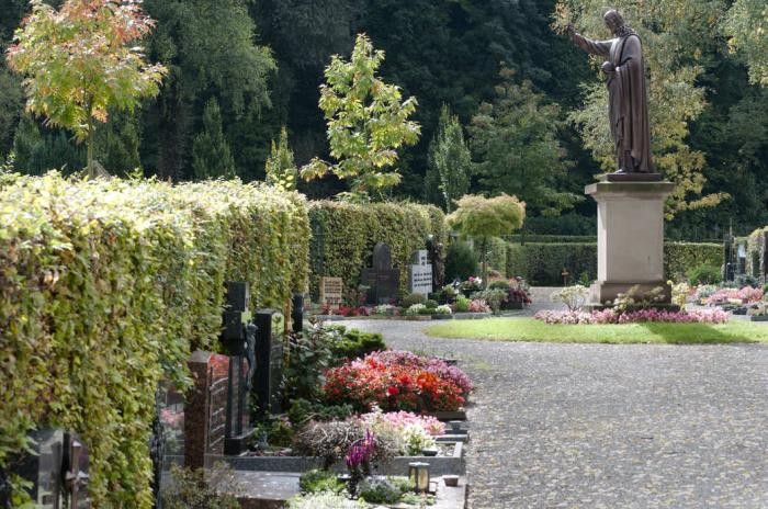 Kiesweg mit Grabanlagen auf der linken Seite und Blick auf Stele auf dem Kreuzbergfriedhof