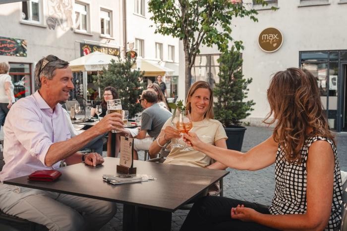 Gäste sitzen an den Tischen des Café Max auf dem Münsterplatz und stoßen an.