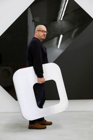 Ein in Schwarz gekleideter Mann hält ein weißes Kunstwerk in der rechten Hand