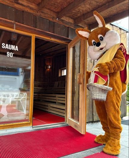 Ein lebensgroßer Plüschosterhase hält die Tür zur Sauna auf, in der Hand einen Osterkorb