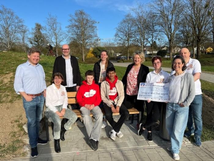 Auf einer Holzbank sitzen Jugendliche, die Mitglieder des Jugendgemeinderates. Auf dem Gruppenfoto außerdem zu sehen sind Männer und Frauen der Stadtverwaltung und des Narrenvereins Plätzlerzunft. 