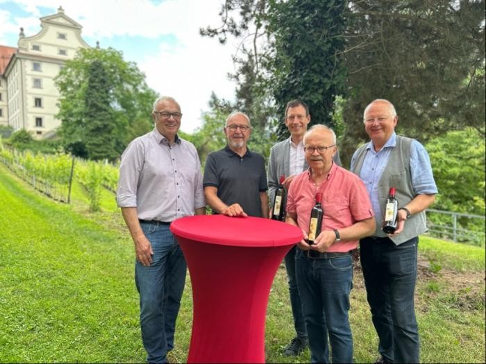 Gruppenbild mit Weinflaschen vor den Reben