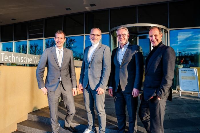 Vier Herren im Anzug vor einem Gebäude