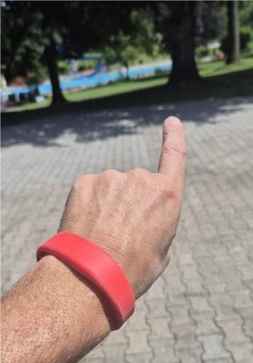 eine ausgestreckte Hand, am Gelenk ein rotes Armband  