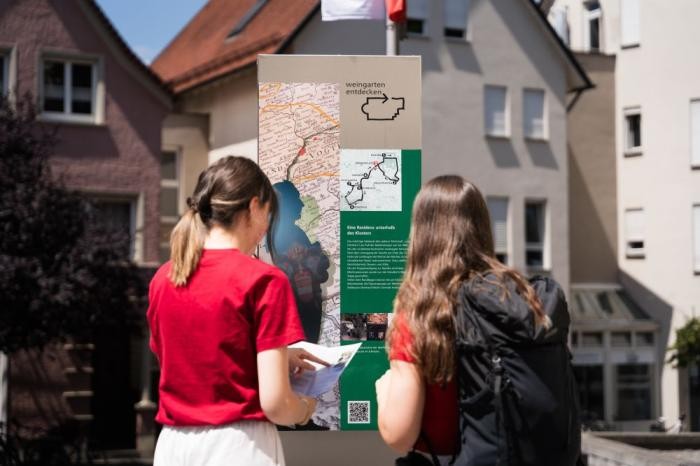 Zwei Frauen sind von hinten zu sehen. Beide schauen eine Karte in der Stadt an
