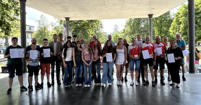 Gruppenbild mit etwa 20 Männern und Frauen, die eine Urkunde in der Hand halten
