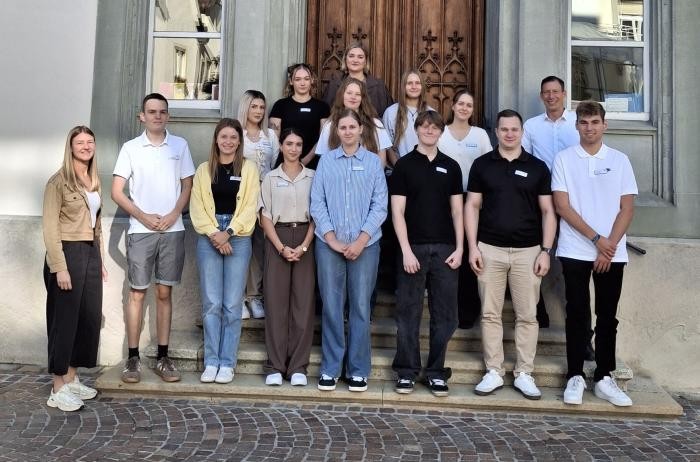Das Gruppenfoto auf einer Treppe zeigt einige junge Männer und Frauen, die in die Kamera lächeln